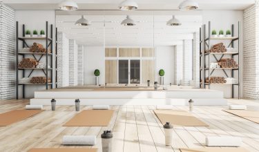 New concrete yoga gym interior with equipment, daylight and wooden flooring. Healthy lifestyle concept. 3D Rendering