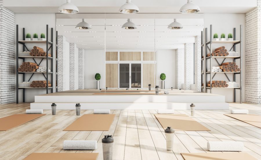 New concrete yoga gym interior with equipment, daylight and wooden flooring. Healthy lifestyle concept. 3D Rendering