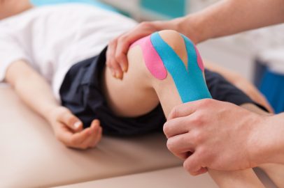 Physiotherapist doing with child exercise for knee